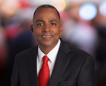 man dressed in a suit and red tie smiling close up