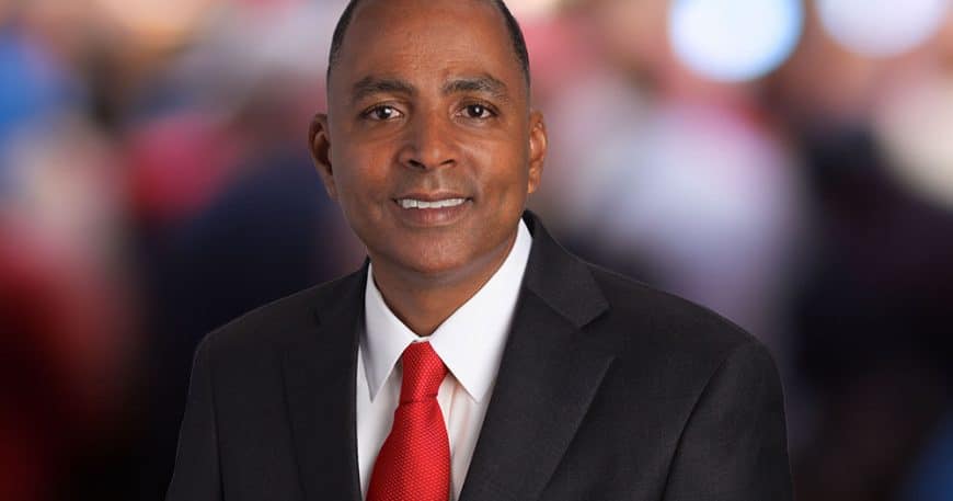 man dressed in a suit and red tie smiling close up