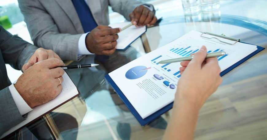 Close-up of human hand with pen pointing at paper while explaining something to colleagues